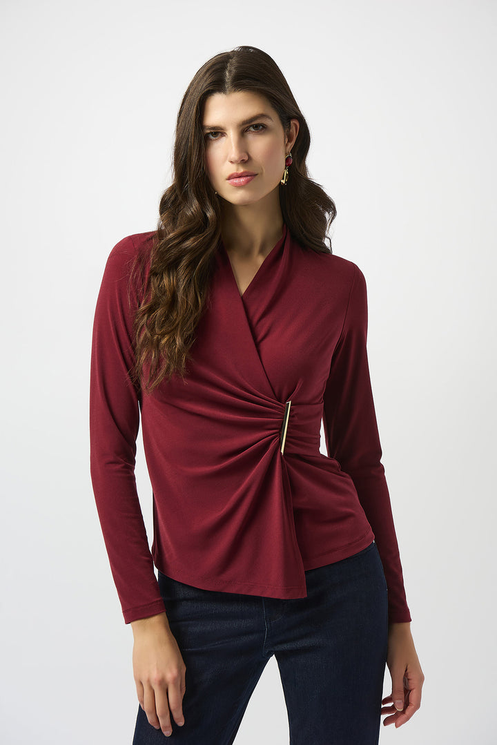 Woman wearing a burgundy long-sleeve top with a knot detail on a white background