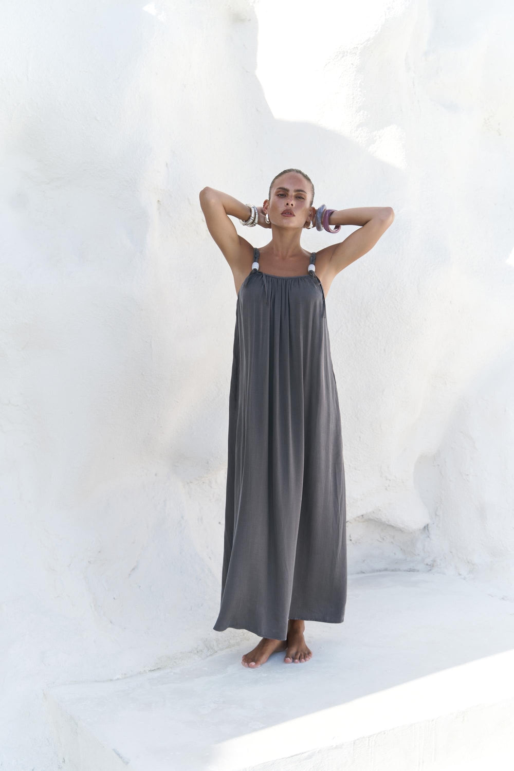 Woman wearing a long gray dress against a white background