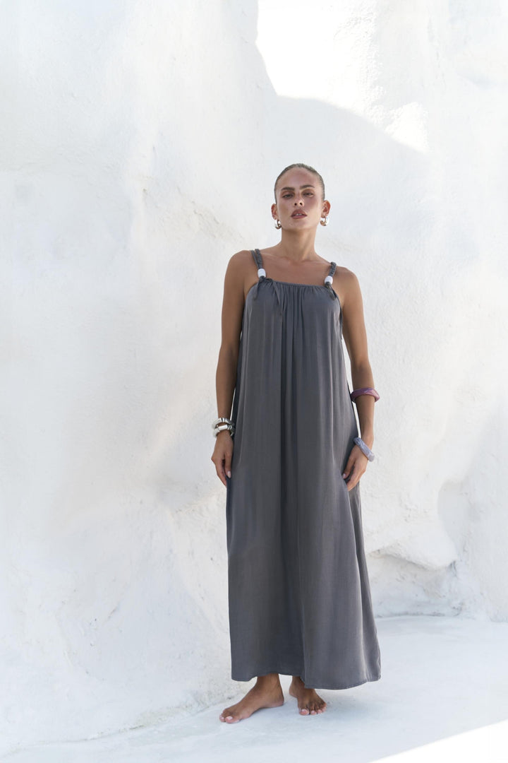 Woman wearing a long gray dress against a white background