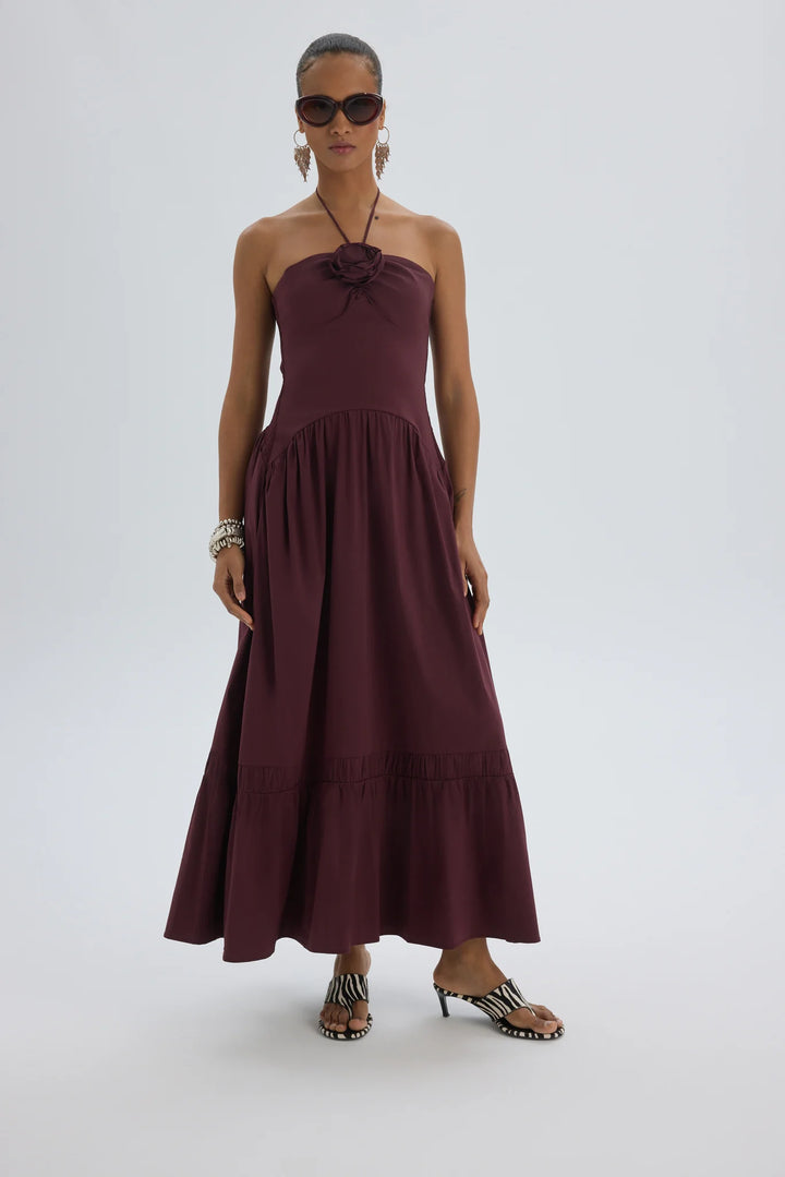 Woman wearing a burgundy halter neck dress on a white background