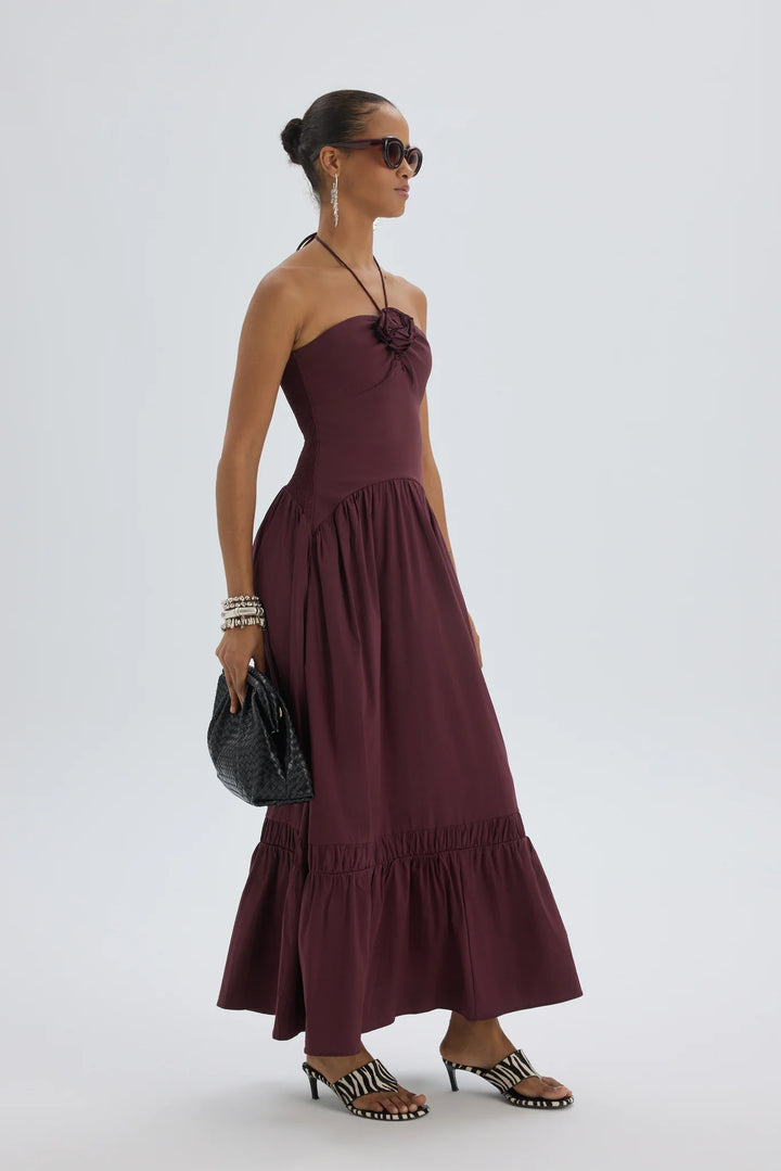 Woman wearing a burgundy dress with ruffled layers on a white background