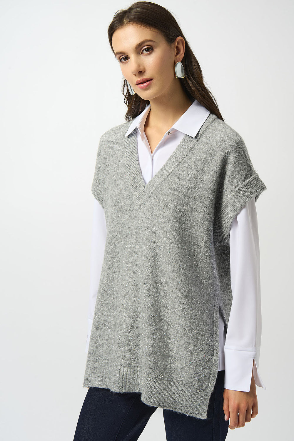 Woman wearing a gray sweater vest over a white shirt on a white background