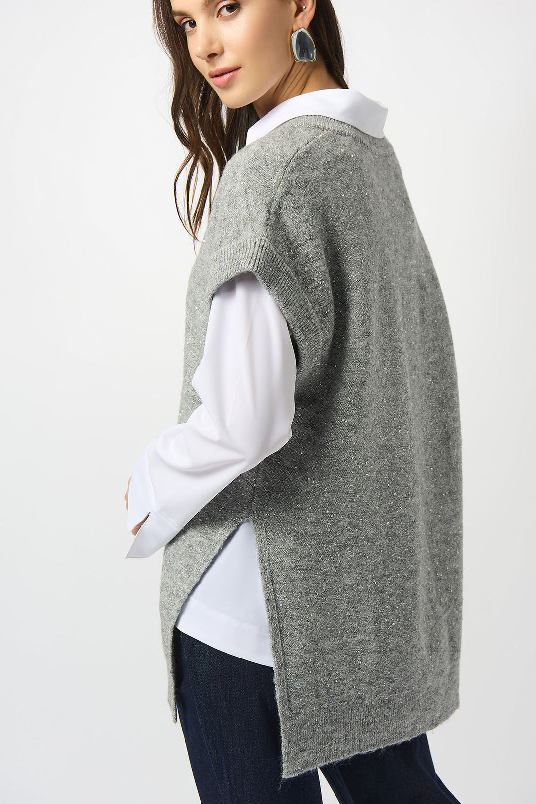 Woman wearing a gray knitted poncho over a white shirt on a white background