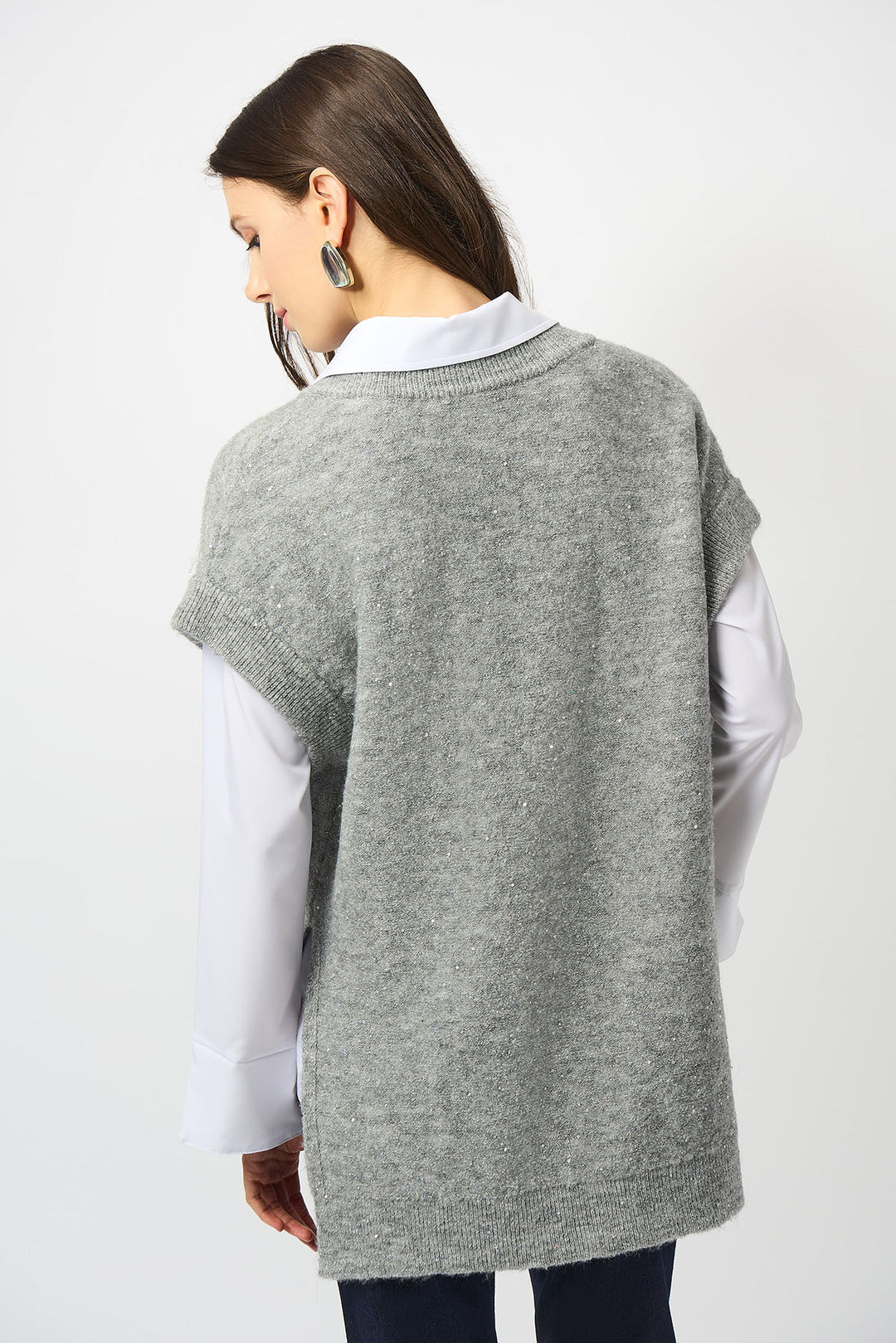 Woman wearing a gray sweater vest over a white shirt on a white background