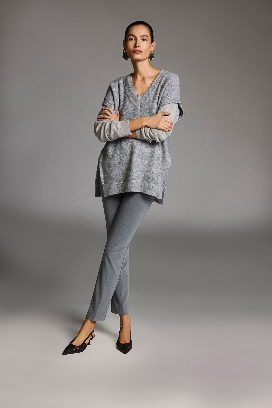 Woman wearing a gray sweater and pants against a gray background