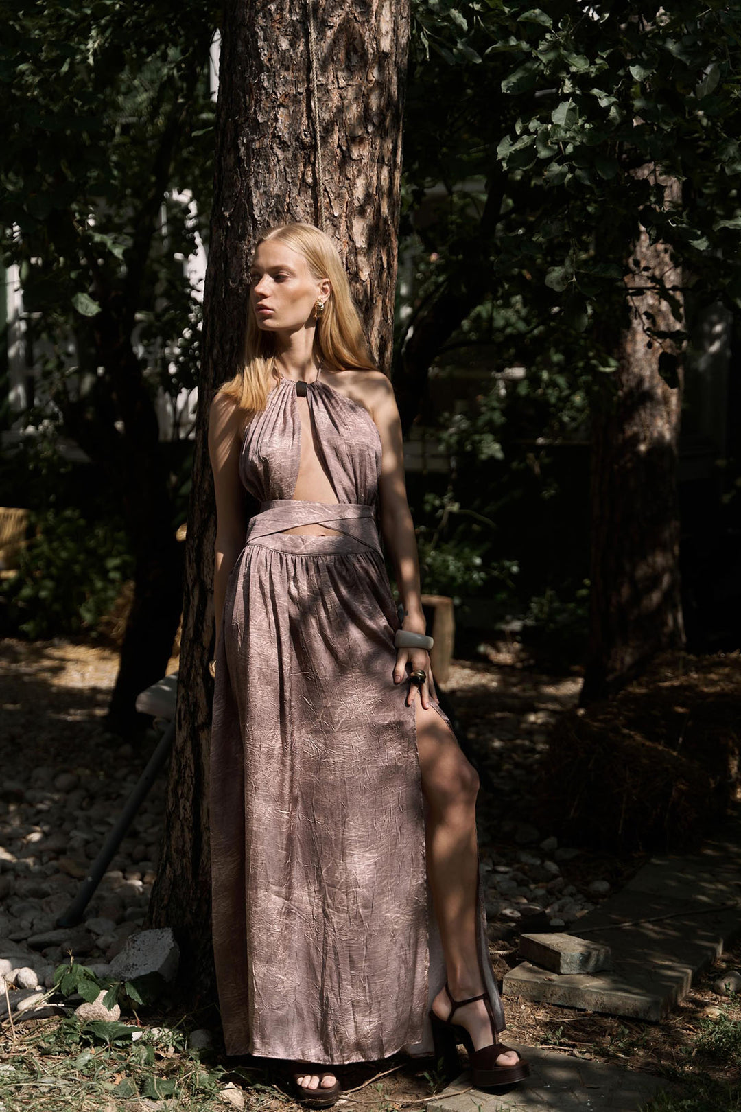 Woman in a long, patterned dress standing in a forest setting