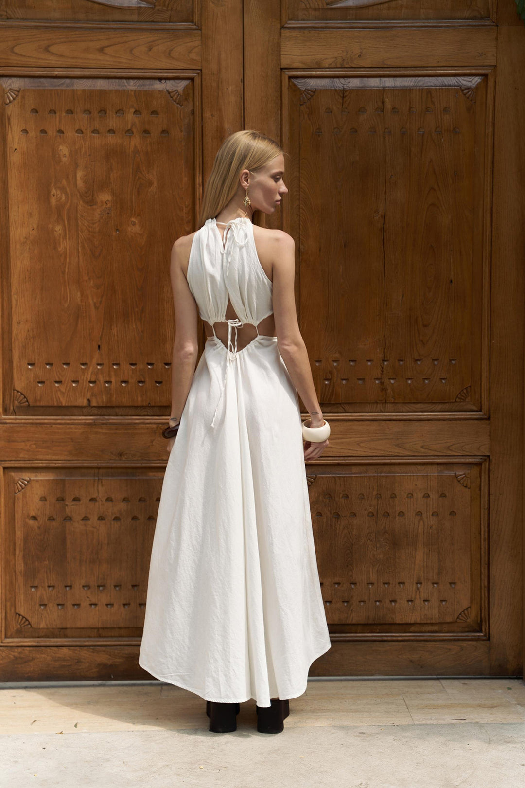 Woman in a white dress standing in front of a wooden door