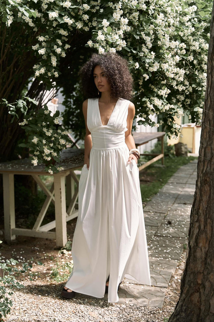 Woman in a white dress standing under a tree with white flowers