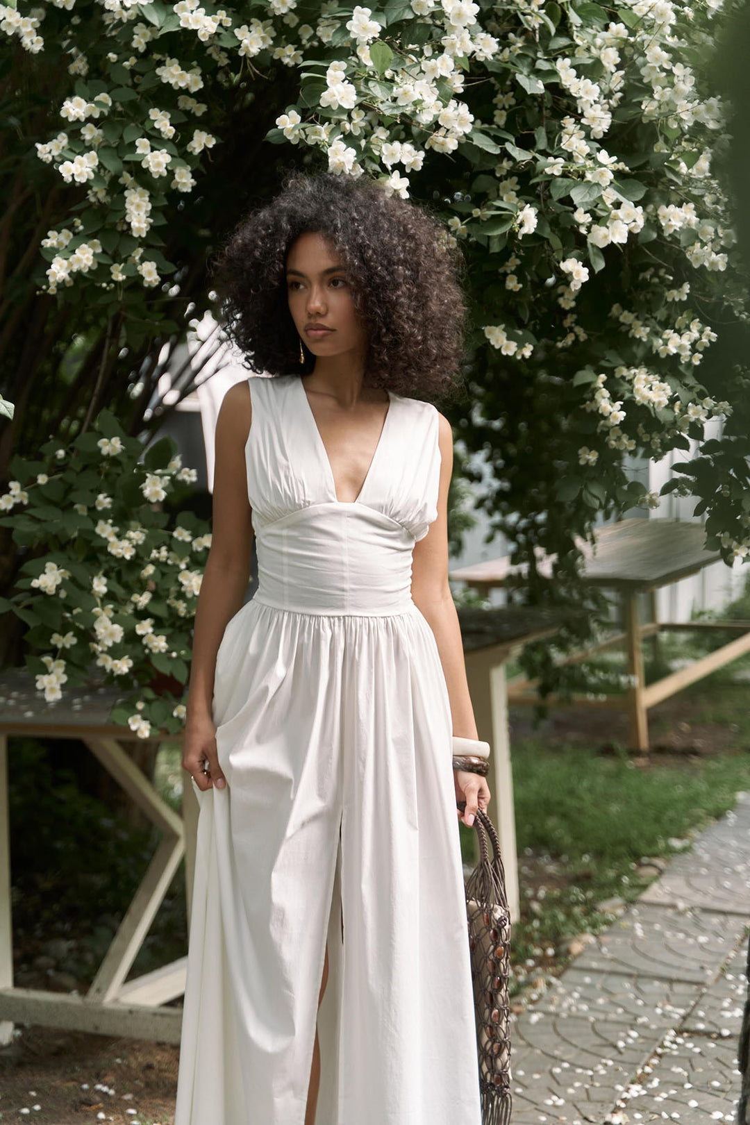 Woman in a white dress standing in front of a flowering bush